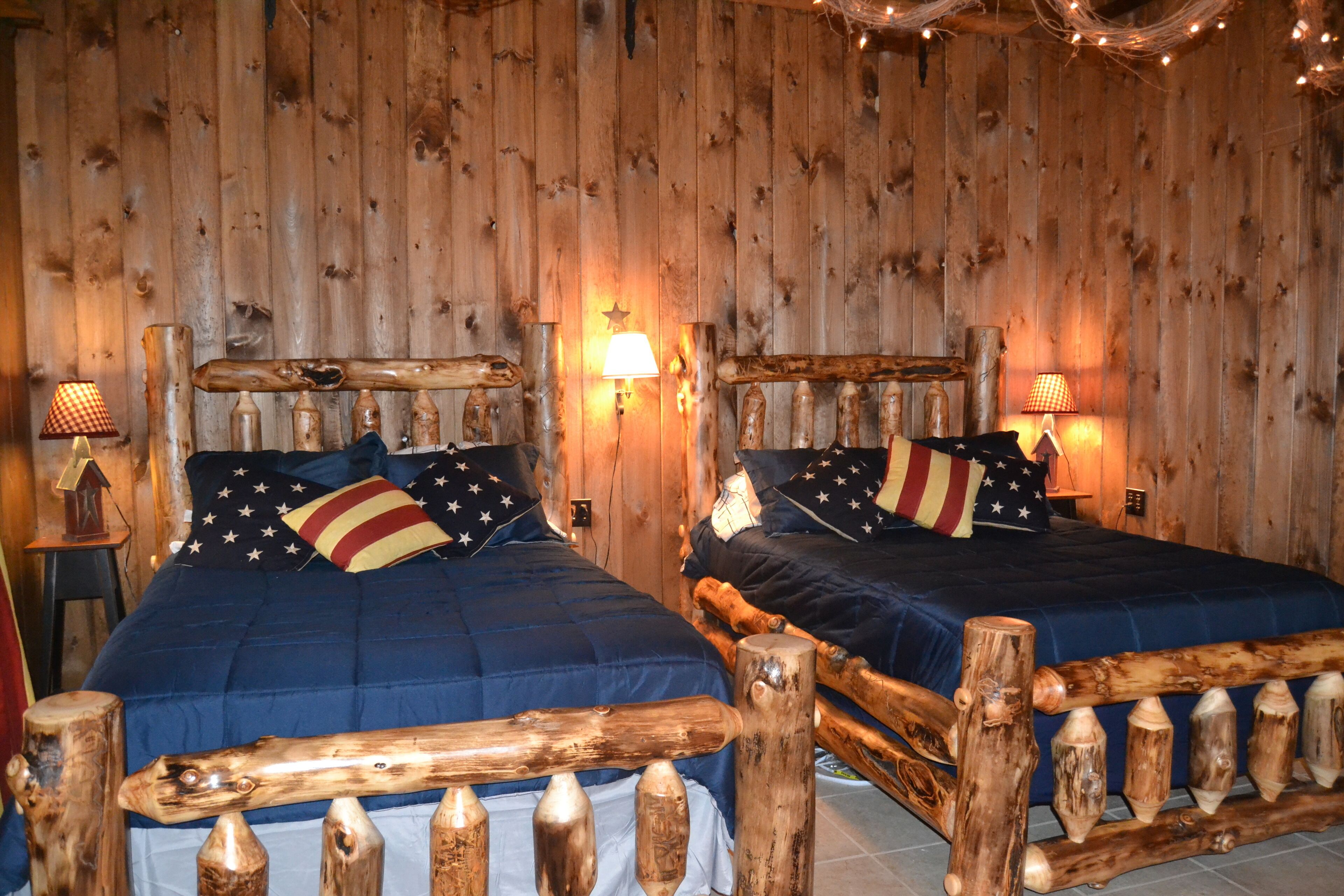 A cabin-style room with two beds, each with a wooden headboard and star-patterned pillows.