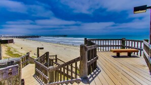 Eine Holzterrasse mit einer Bank mit Blick auf einen Strand und einen Steg.
