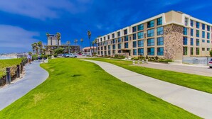 A modern building with a stone facade, a paved walkway, and a grassy area.