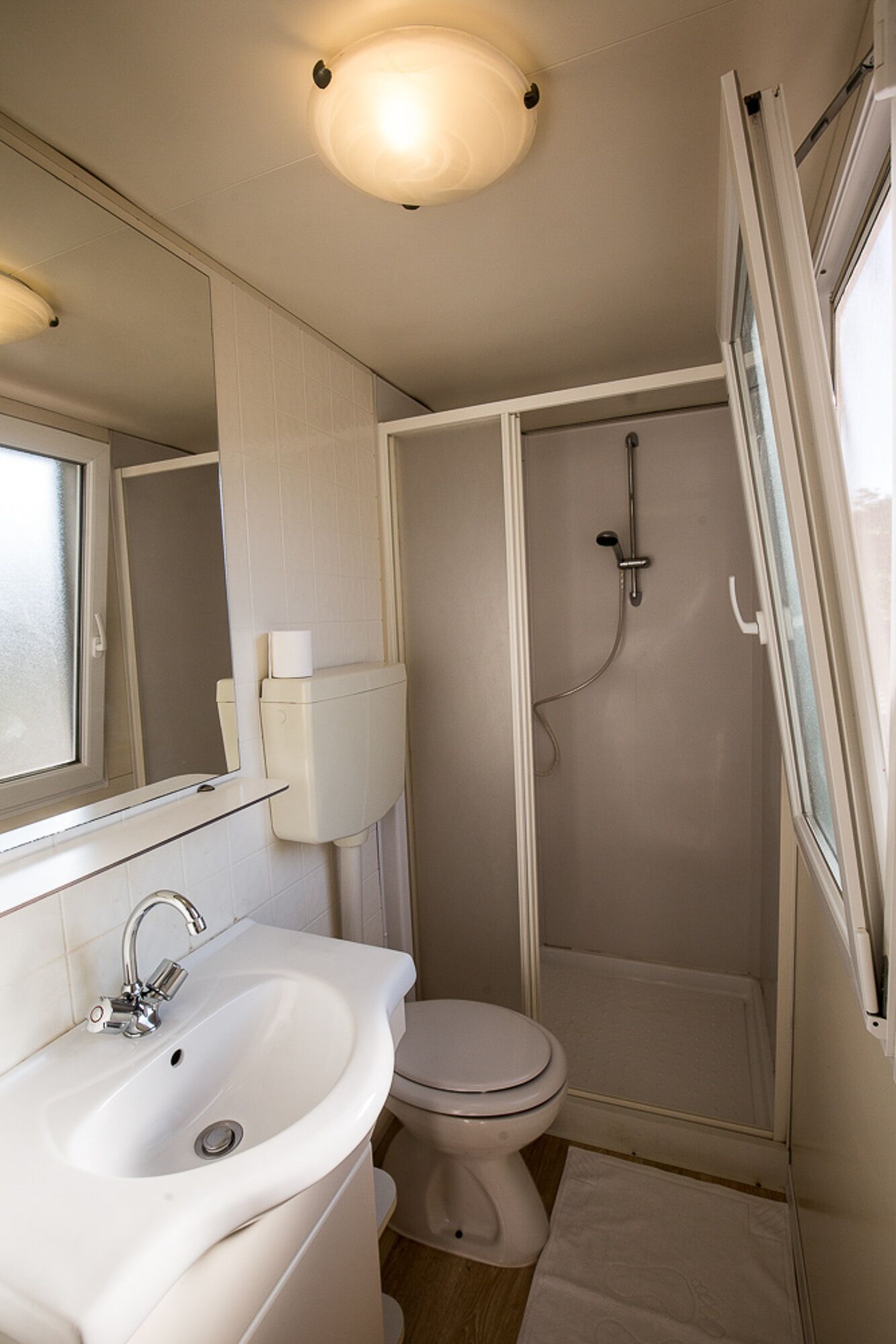 A compact bathroom with a sink, toilet, and shower.