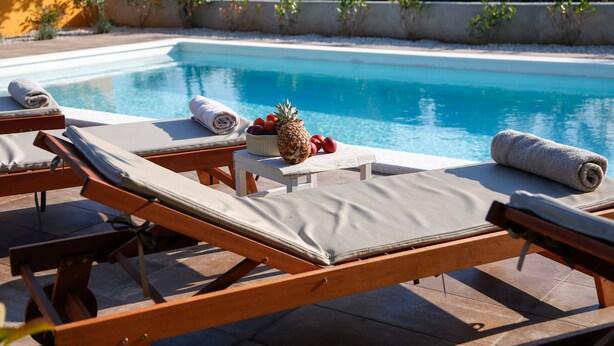 A poolside area with lounge chairs, towels, and a bowl of fruit.