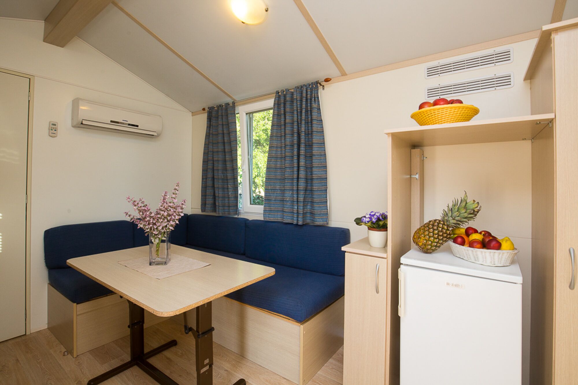 Une petite cuisine équipée comprenant un réfrigérateur, une petite table et un canapé bleu.