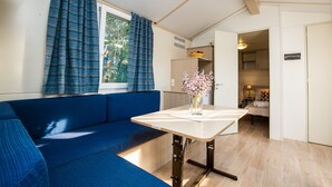 A room with a blue sofa, a small table with a vase, and a window with curtains.