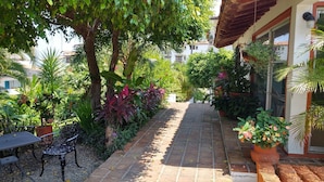 A garden patio with a brick pathway, potted plants, and outdoor furniture. - Newly Listed Amazing, Serene resort with Beautiful Sunsets & Blue Waters  (PUERTO VALLARTA)