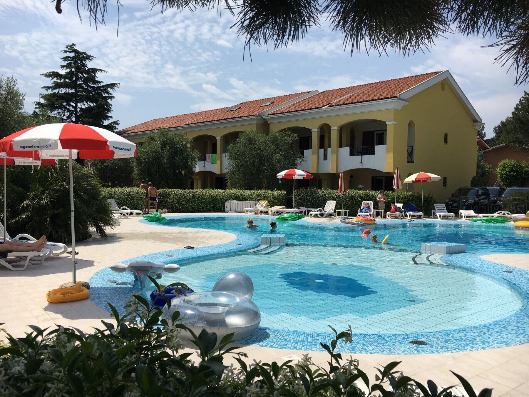 A swimming pool with multiple lanes, surrounded by lounge chairs and umbrellas.
