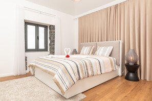 Ein Schlafzimmer mit Bett, Nachttisch, Lampe, Fenster und Vorhängen.
