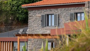 A stone building with a balcony, a wooden pergola, and a view of the surrounding greenery. - BHF Residences Ying Yang (Calheta)