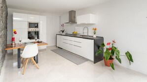 A modern kitchen with white cabinetry, a built-in oven, and a black countertop. - BHF Residences Ying Yang (Calheta)