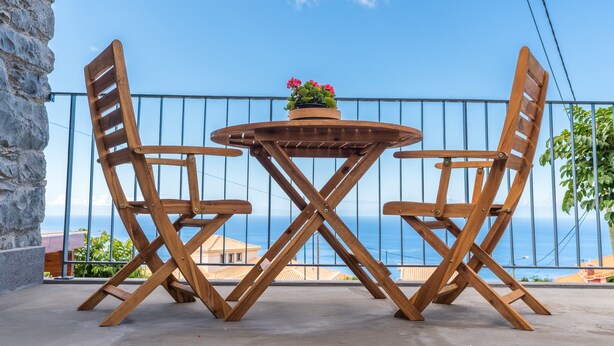 A wooden table and chairs on a balcony with a view of the sea. - BHF Residences Ying Yang (Calheta)