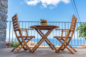 Una mesa y sillas de madera en un balcón con vista al mar.