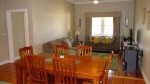 Un comedor con una mesa y sillas de madera, un sofá y una televisión en una sala de estar.