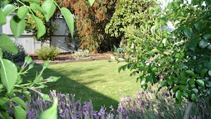 Un jardín bien cuidado con césped, arbustos variados y plantas en flor.
