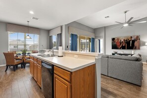 A modern kitchen with a central island, wooden cabinets, and a dining area with wicker chairs.