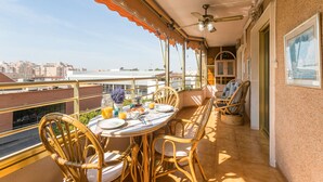 Ein Balkon mit Frühstückstisch, Korbstühlen und Blick auf die Stadt.