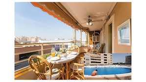 Ein Balkon mit Esstisch, ein Pool und Blick auf die Stadt.