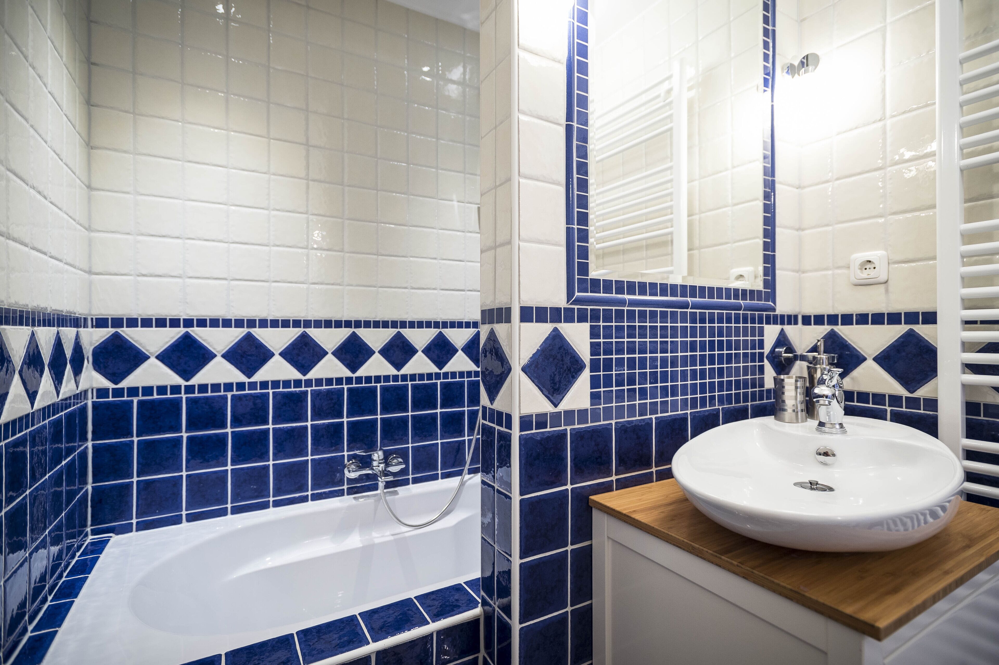A bathroom with a bathtub, a sink, and blue and white tiles.