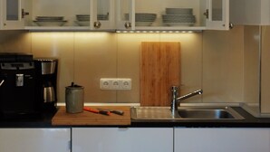 Een moderne keuken met een koffiezetapparaat, een spoelbak en een houten snijplank.