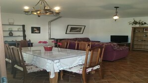 A dining area with a glass table, chairs, and a chandelier. There is a sofa and a television in the living area. - HOUSE WITH PRIVATE PLOT - CONIL DE LA FRONTERA (FREE WIFI) (Conil de la Frontera)