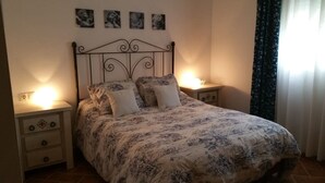 A bedroom with a bed, two bedside tables, a nightstand, a wall-mounted lamp, and a window with curtains. - HOUSE WITH PRIVATE PLOT - CONIL DE LA FRONTERA (FREE WIFI) (Conil de la Frontera)