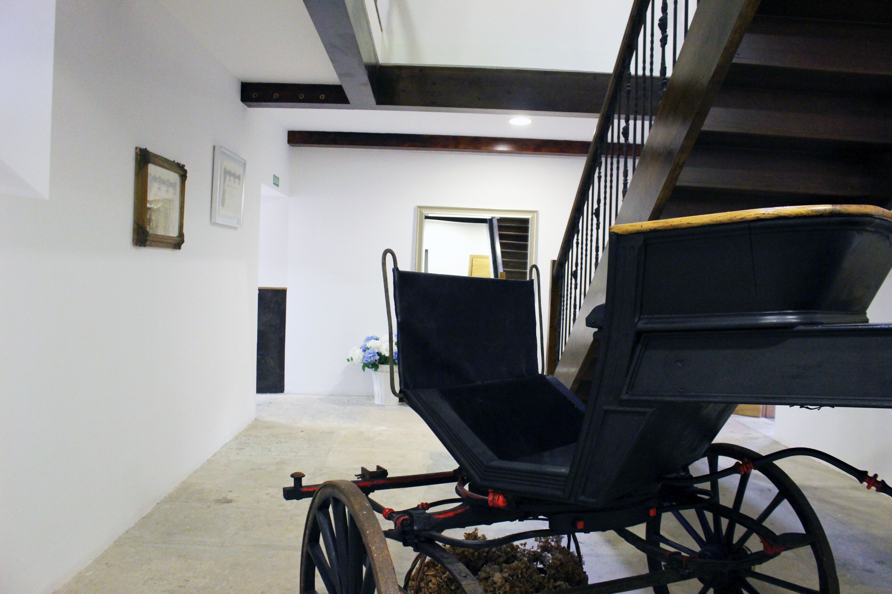 Un carruaje en un pasillo con paredes blancas y techo de madera.