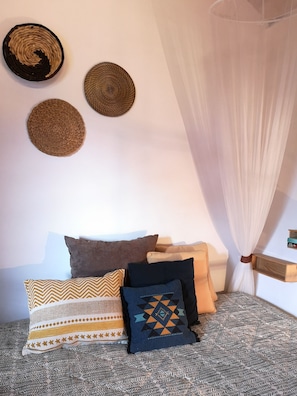 A bedroom with a bed, a canopy, and three wall-mounted woven baskets.