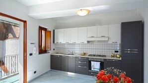 Eine moderne Küche mit grauen Schränken, einer gefliesten Spritzschutzwand und einem eingebauten Backofen.