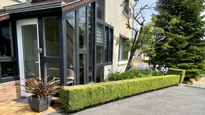 A modern building with large glass windows, a well-maintained hedge, and a potted plant. - LA VERANDA (VERDIGNY)