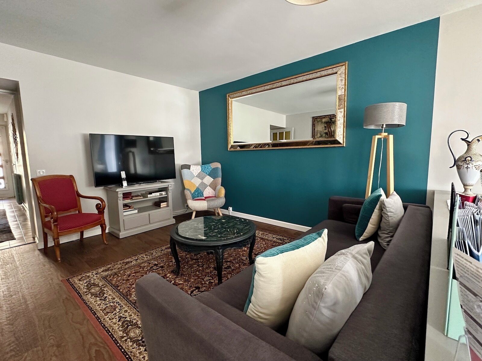 Una sala de estar con sofá, sillón, televisor y un espejo grande.