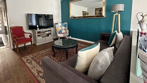 A living room with a sofa, armchair, TV, and a large mirror. - LA VERANDA (VERDIGNY)