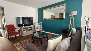 Una sala de estar con sofá, sillón, televisor y un espejo grande.