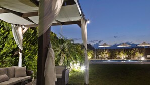 Un espace extérieur aménagé en terrasse, avec une piscine, des chaises longues et des parasols.