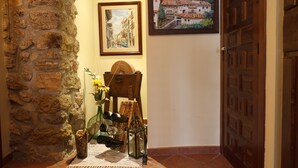 A stone wall, a wooden door, a framed painting, and a table with bottles and a vase. - ALZINA apartment in the heart of the Penedés. PB-00489 (Pontons)