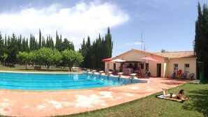 A rectangular swimming pool with a surrounding deck, a small lifeguard stand, and a building with outdoor seating. - ALZINA apartment in the heart of the Penedés. PB-00489 (Pontons)