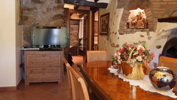 A rustic dining area with a wooden table, chairs, and a fireplace. - ALZINA apartment in the heart of the Penedés. PB-00489 (Pontons)