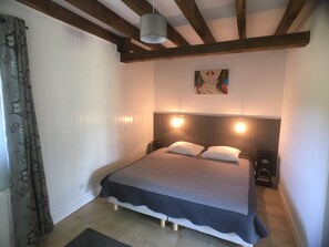 Cozy retreat with a bed, wall-mounted light, and a beautiful painting.
