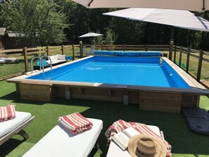 Relax by the pool surrounded by a shaded deck with lounge chairs and towels.