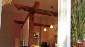 A dining area with a wooden beam ceiling, a chandelier, and a view of a kitchen through a window. - stylish and nostalgic near Timmendorfer Strand Baltic Sea and old town Lübeck (Offendorf)