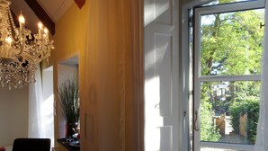 A dining area with a chandelier, a table set with plates and a candle, and a view of a garden through a glass door. - stylish and nostalgic near Timmendorfer Strand Baltic Sea and old town Lübeck (Offendorf)
