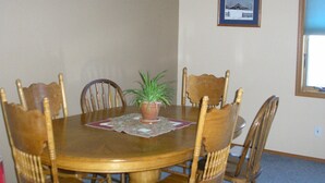 Una mesa de comedor con seis sillas de madera, una planta en maceta y un cuadro en la pared.