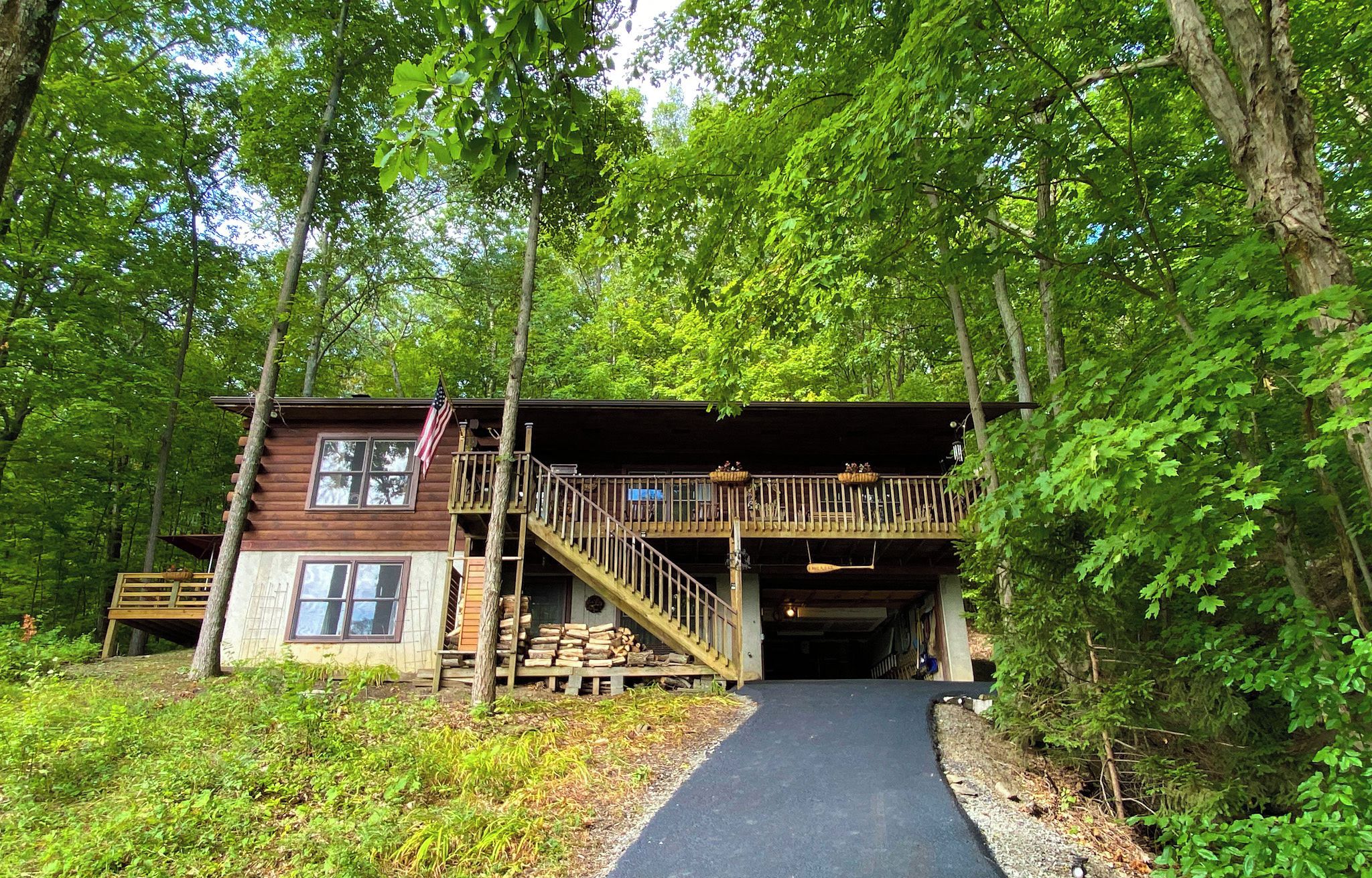 A cabin with a wooden exterior, a covered porch, and a staircase leading to a deck.