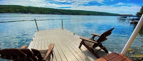 Eine Holzterrasse mit Adirondack-Stühlen mit Blick auf einen See, der nach Süden führt.