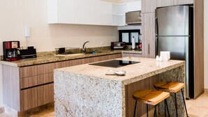 Una cocina moderna con encimeras de granito, electrodomésticos de acero inoxidable y taburetes de bar de madera.