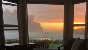 A room with a view of a sunset over a body of water, a chair, and a table. - Prime Ocean/Beach Location & Spectacular View!Ground Level Condo,Fresh Update (Neskowin)