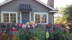 A house with a blue door and windows, surrounded by a garden with various flowers. - Prime Ocean/Beach Location & Spectacular View!Ground Level Condo,Fresh Update (Neskowin)