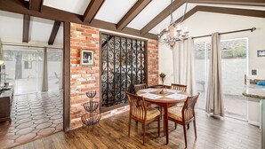 A dining area with a brick wall, a wrought iron gate, and a chandelier.