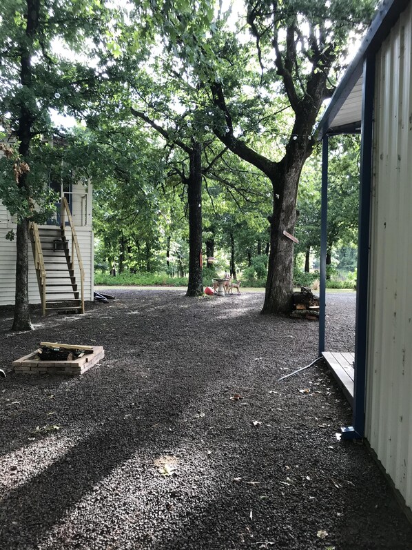 Surrounded by mature trees, this outdoor space offers a tranquil retreat with a wooden ladder leading to an upper level and a small brick feature.