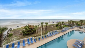 Ein Pool mit blauen Stühlen und Blick auf den Strand.
