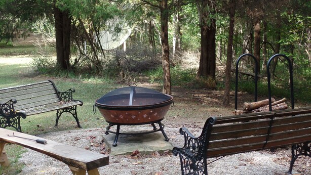 Un parque con un hogar para fuego, bancos y una mesa de picnic.