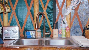 Una cocina con un lavamanos de acero inoxidable, un tostador, un dispensador de jabón para manos y una botella de detergente.