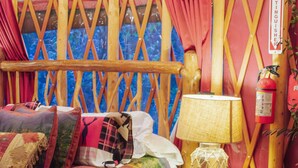 Una habitación acogedora y rústica con una cama de madera, una mesita con una lámpara y un extintor en la pared.